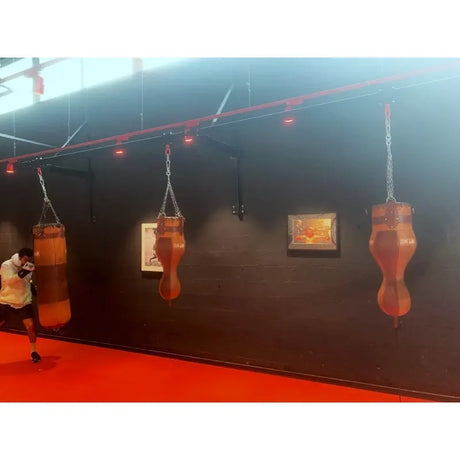 SportCom Vintage 3-in-1-Sandsack Echtleder, mehrere Säcke an einer dunklen Wand im Boxstudio