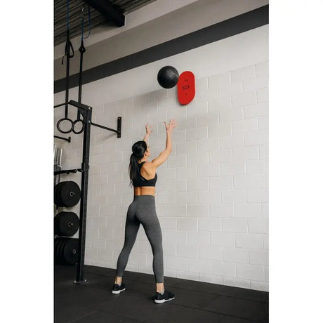 SportCom Wandballziel Pro gemischtes Modell im Studio: Sportlerin wirft einen Medizinball an die Zielplatte