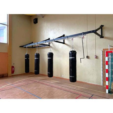 SportCom Wandmontierte Schiene für Sandsäcke, in einer Turnhalle mit vier Sandsäcken und Seilzug