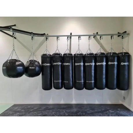 SportCom Wandmontierte Schiene für Sandsäcke, mit Sandsäcken und zwei Maisbirnen an weißer Wand