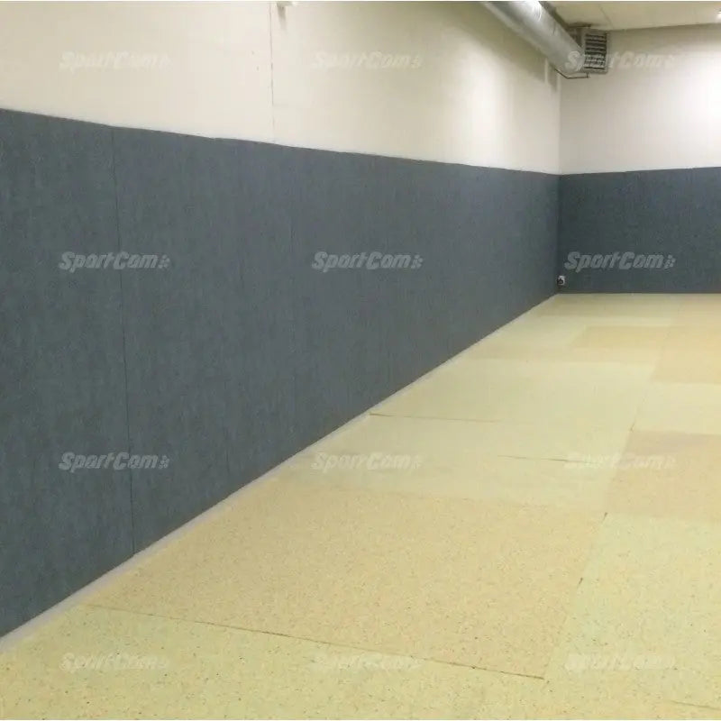 SportCom Wandpolster Standard, graue Polster entlang einer Wand über beigem Mattenboden