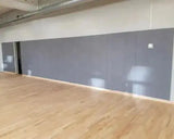 SportCom Wandpolster Standard SC-16211, graue Polster an der Wand einer Halle mit Parkettboden