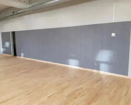 SportCom Wandpolster Standard SC-16211, graue Polster an der Wand einer Halle mit Parkettboden