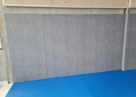 SportCom Wandpolster Standard SC-16211, graue Wandplatten zwischen Betonpfeilern über blauen Matten