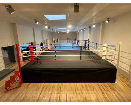 SportCom Wettkampf-Boxring mit 1 m Podium, in einer hellen Halle mit Holzboden