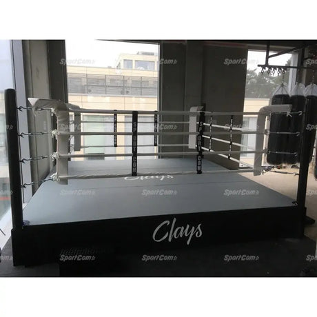 SportCom Wettkampf-Boxringseil mit Hülle, erhöhter Boxring mit weißen Seilen in einem Gym mit Fensterfront