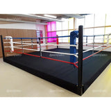 SportCom Wettkampf-Boxringseil mit Hülle, erhöhter Boxring mit roten und weißen Seilen in heller Halle