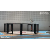 SportCom Wettkampf-MMA-Käfig 7 m auf Podium, seitlich in einer hellen Sporthalle mit Basketballkorb
