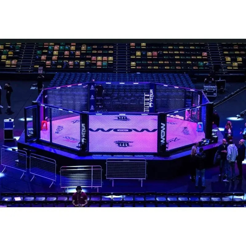 SportCom Wettkampf-MMA-Käfig Performance Oktagon, in einer Arena mit blauer Beleuchtung und vollen Tribünen