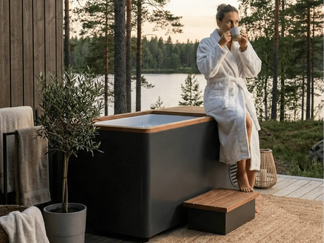 Swedish Cold Generation 4S Eisbad – Frau im Bademantel neben der Wanne auf einer Holzterrasse am See