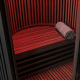 Swedish Cold Sanctuary Solo Infrarotsauna, Detail der Holzbank mit Handtuch im rot beleuchteten Innenraum