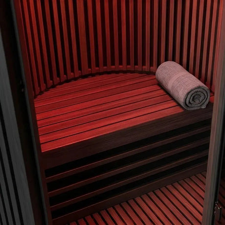 Swedish Cold Sanctuary Solo Infrarotsauna, Detail der Holzbank mit Handtuch im rot beleuchteten Innenraum