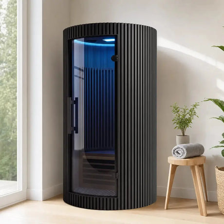 Swedish Cold Sanctuary Solo Infrarotsauna in Schwarz in einem hellen Wohnraum mit Pflanze und Hocker