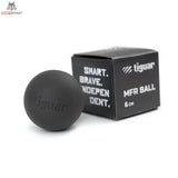 tiguar MFR Ball Massageball hart in Schwarz neben der schwarzen Verpackung, Schrägansicht