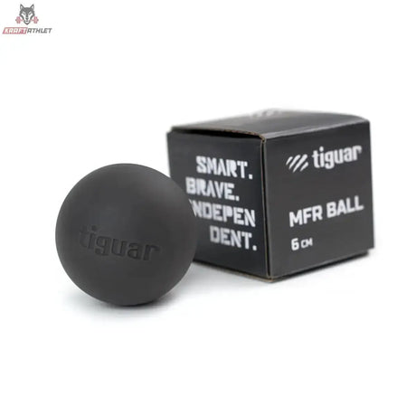 tiguar MFR Ball Massageball hart in Schwarz neben der schwarzen Verpackung, Schrägansicht