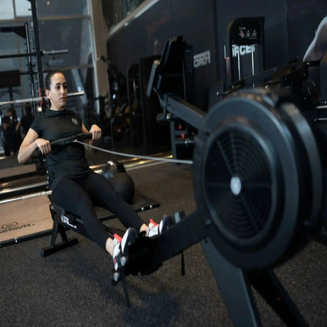 Titanium Strength Air Rowing Machine Rudergerät im Studio mit Sportlerin beim Rudern, Nahansicht des Luftrads