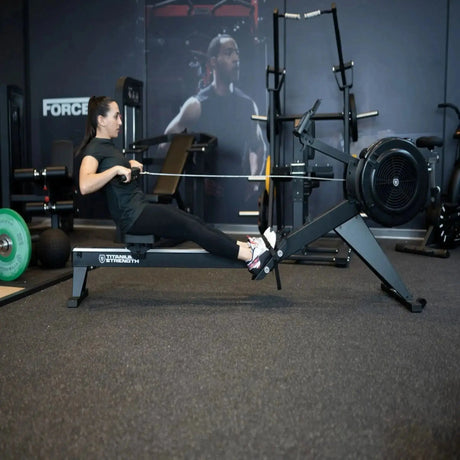 Titanium Strength Air Rowing Machine Rudergerät im Studio beim Rudertraining einer Sportlerin in der Zugphase