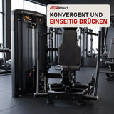 Titanium Strength Genesis Series Unilaterale Vertikale Brustpresse in einem fertig eingerichteten Studio mit dunklen Wänden und Gummiboden