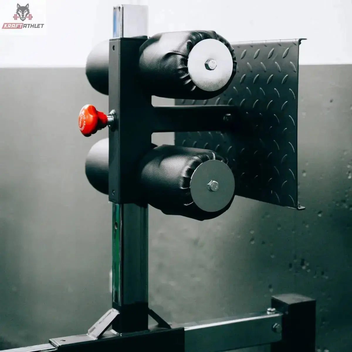 Titanium Strength Glute Ham Developer GHD GH130, Detail der Fersenrollen am Fußteil vor Riffelblech-Wand