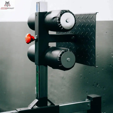 Titanium Strength Glute Ham Developer GHD GH130, Detail der Fersenrollen am Fußteil vor Riffelblech-Wand