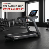Titanium Strength TM900 TFT Laufband mit 16-Zoll-Touchscreen in einem fertig eingerichteten Studio mit dunklen Wänden und Gummiboden