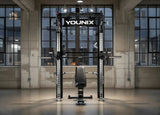 Younix Cable Rack Smith Bundle Komplettpaket mit Smith Machine, frontal in einem Loft mit großen Fenstern und Hantelbank