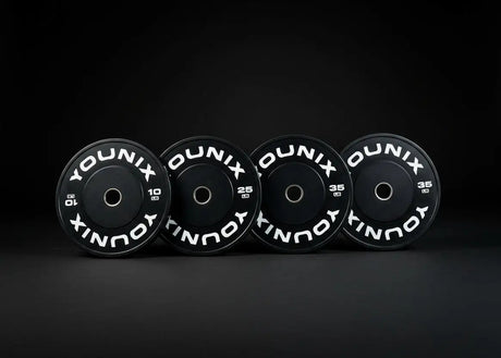 Younix Premium Bumper Set 100 kg Hantelscheiben-Set, vier schwarze Scheiben stehend vor dunklem Hintergrund