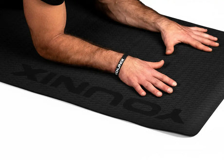 Younix Workout Mat Trainingsmatte in Schwarz, Hände abgestützt neben dem geprägten Schriftzug